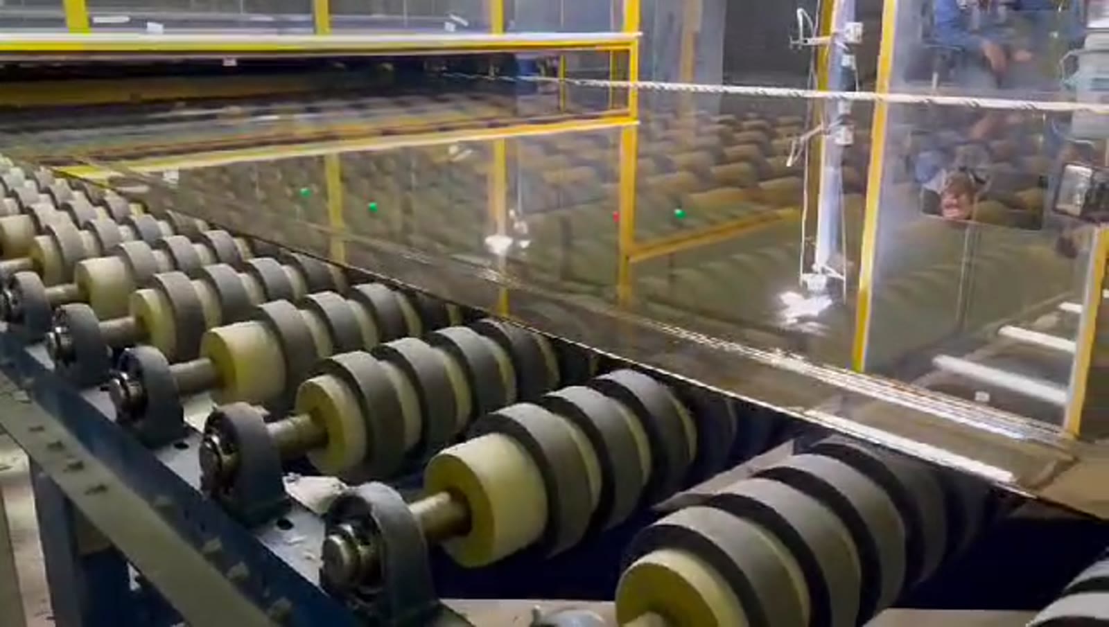 Glass sheet moving through production line rollers